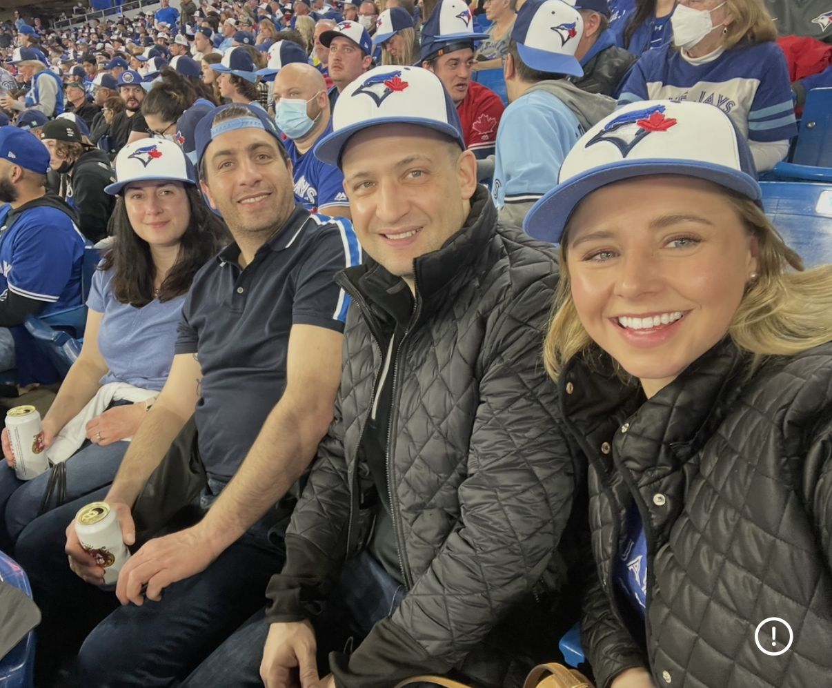 Brittany and a group posing together in Toronto Blue Jays gear in the stadium stands